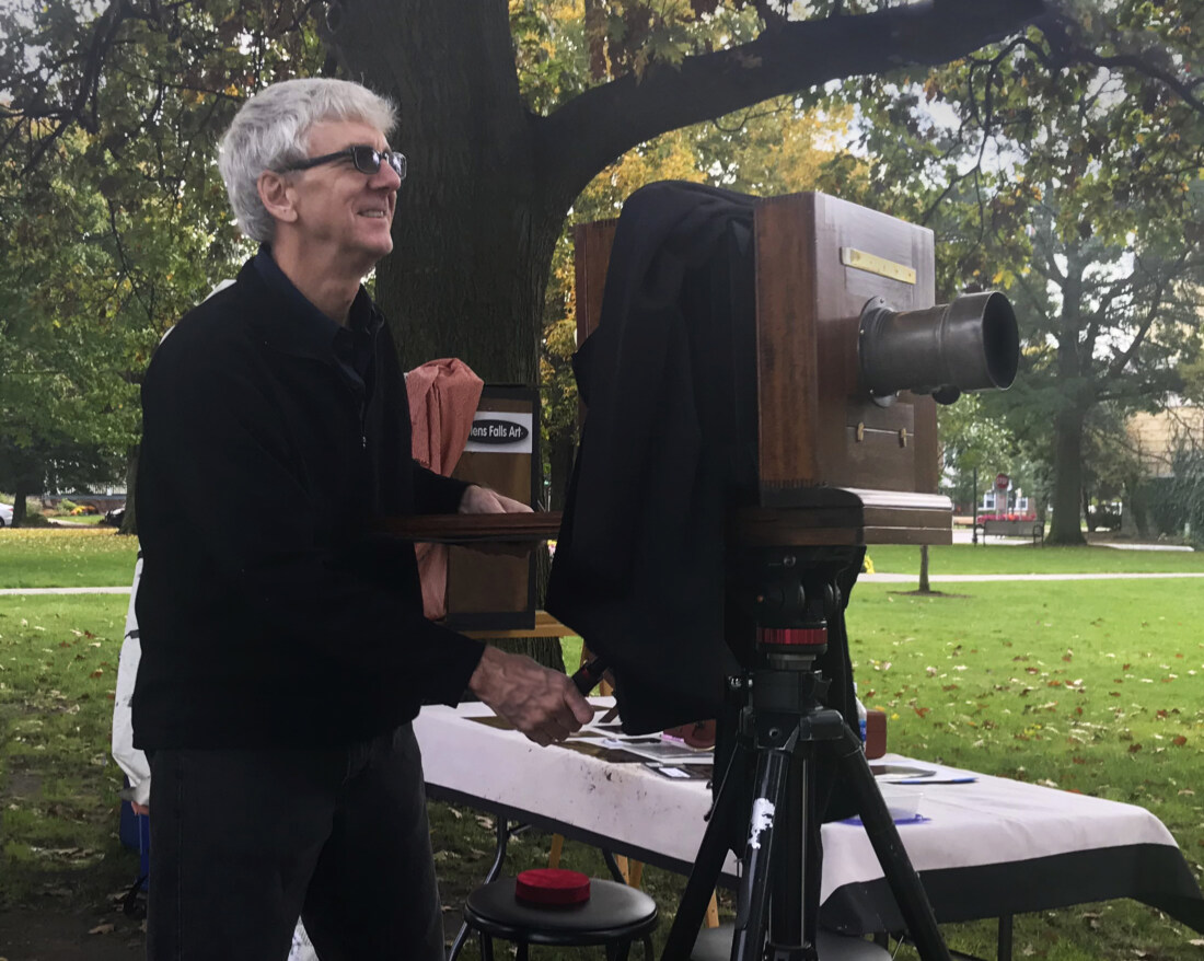 collodion photographer Craig Murphy with his reproduction camera and 19th century lens and glens falls art traveling tintype studio in glens falls city park.